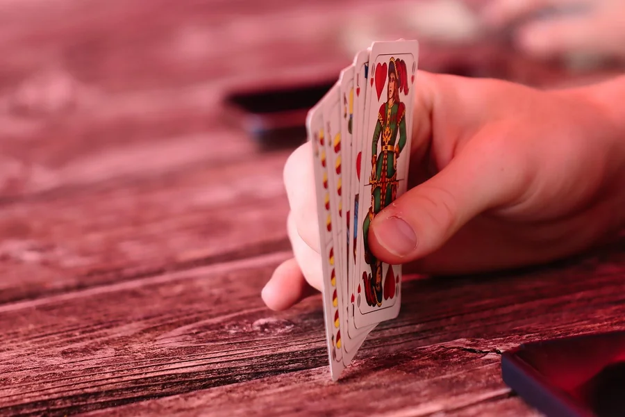 A hand holding cards on a table.